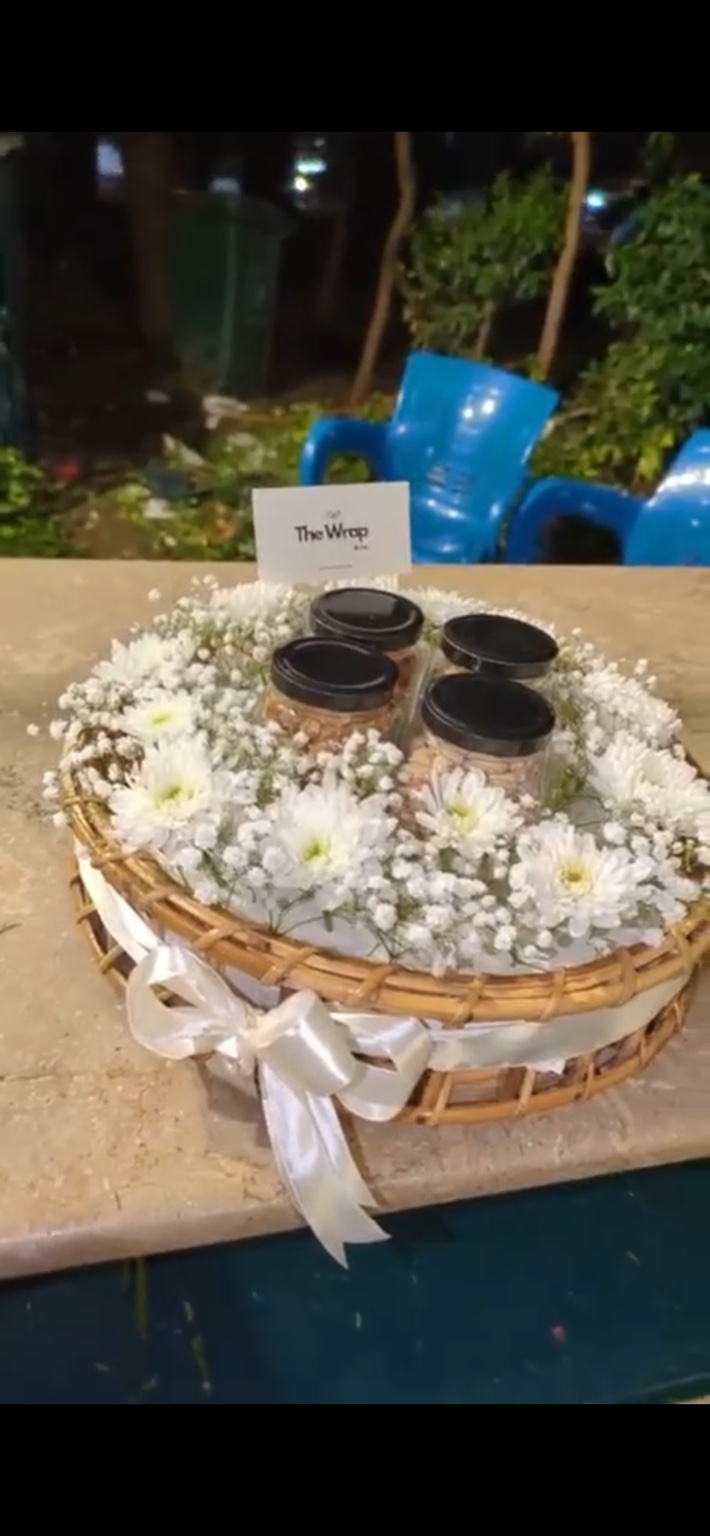 The Wrap & Co. dry-fruit basket with four jars, white chrysanthemums, baby’s breath and a satin bow